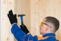 Man in construction clothes and goggles nails the board with nails and a hammer Royalty Free Stock Photo