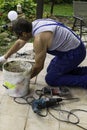 Man construction worker laying floor tile, perforator, drill tools selective focus, renovation outdoor