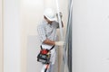Man construction worker or plasterer holding drywall metal profiles near plasterboard white wall in building site. Wearing white Royalty Free Stock Photo