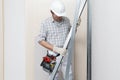 Man construction worker or plasterer holding drywall metal profiles near plasterboard white wall in building site. Wearing white Royalty Free Stock Photo