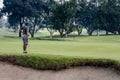 A man contemplates his putt on golfing green.