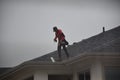 A man contractor worker on roof top working on a cloudy rainy day.standing sitting walking kneeling. fixing roof.rain water system