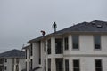 A man contractor worker on roof top working on a cloudy rainy day.standing sitting walking kneeling. fixing roof.rain water system