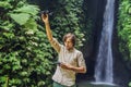 The man controls the drone against the background of the forest and the waterfall Royalty Free Stock Photo
