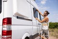 Man installing a window on the side of a camper van