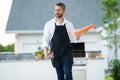 Man in cook apron grilling and barbequing salmon fish in garden. Handsome man preparing barbecue salmon fillet. Barbecue Royalty Free Stock Photo