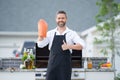 Man in cook apron grilling and barbequing salmon fish in garden. Handsome man preparing barbecue salmon fillet. Barbecue Royalty Free Stock Photo