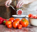 Man cook grinds pieces of ripe tomatoes into an old vintage hand-grinder for cooking homemade sauce, ketchup Royalty Free Stock Photo