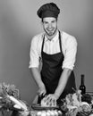 Man in cook hat and apron cuts cabbage. Cook works in kitchen near table with vegetables and tools. Royalty Free Stock Photo