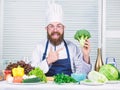 Man cook hat and apron hold broccoli. Healthy nutrition concept. Bearded professional chef cooking healthy food. Healthy Royalty Free Stock Photo