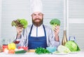 Man cook hat and apron hold broccoli. Organic vegetables. Healthy nutrition concept. Bearded professional chef cooking Royalty Free Stock Photo