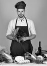 Man in cook hat and apron with salad. Cook works in kitchen with vegetables and tools. Royalty Free Stock Photo