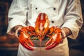 A man cook holds a cooked lobster in his hands