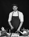 Man in cook uniform chops pepper. Chef with happy face Royalty Free Stock Photo