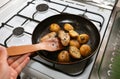 Man cooking chicken wings with potatoes lying on the frying pan on the oven. Homemade lunch. Unhealthy food photo with fat Royalty Free Stock Photo