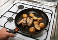 Man cooking chicken wings with potatoes lying on the frying pan on the oven. Homemade lunch. Unhealthy food photo with fat Royalty Free Stock Photo