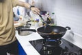 Man cooking fried chicken in kitchen of home He holds spatula and pan. with gas stove that is frying thai food for family Royalty Free Stock Photo