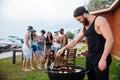 Man cooking grilled sauseges and vegetables on barbeque party