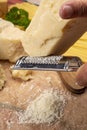 Man cooking with hard italian cheese, grated parmesan or grana padano cheese, hand with grater Royalty Free Stock Photo
