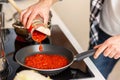 Man cooking at home kitchenn adding sauce to pan. Royalty Free Stock Photo