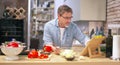 Man cooking in kitchen at home reading recipe on tablet Royalty Free Stock Photo