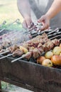 Man cooking marinated shashlik or shish kebab, chiken meat grilling on metal skewer, close up. Selective focus Royalty Free Stock Photo