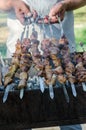 Man cooking marinated shashlik or shish kebab, chiken meat grilling on metal skewer, close up. Selective focus Royalty Free Stock Photo