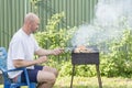 Man cooking meat on barbecue. Young couple making barbecue in their garden. Man cooking meat on barbecue Royalty Free Stock Photo