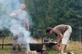 Man Cooking Meat Over Bonfire At Campsite