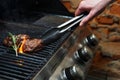 Man cooking meat steaks on professional grill outdoors Royalty Free Stock Photo
