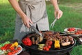 Man cooking meat and vegetables on barbecue grill outdoors, closeup Royalty Free Stock Photo