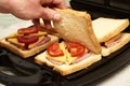 a man cooking sandwiches in a sandwich maker puts a piece of bread in a mold Royalty Free Stock Photo