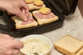 a man cooking sandwiches in a sandwich maker spreads garlic sauce on bread Royalty Free Stock Photo