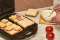 a man cooking sandwiches in a sandwich maker spreads garlic sauce on bread Royalty Free Stock Photo