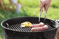 Man cooking sausages and vegetables on barbecue grill outdoors, closeup Royalty Free Stock Photo