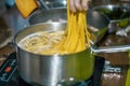 MAN COOKING SPAGHETTI PASTA IN PAN OF BOILING WATER ON COOKER HOB Royalty Free Stock Photo