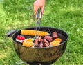 Man cooking tasty vegetables, sausages and meat on barbecue grill outdoors Royalty Free Stock Photo