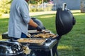 A man cooks chicken meat on skewers on a grill in the garden in the summer during a barbecue party Royalty Free Stock Photo