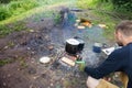 A man cooks on a fire, a tourist heats water in a pot on a fire