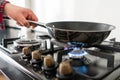 A man cooks in a frying pan, puts it on the stove. Modern gas burner and hob on a kitchen range. Dark black color and Royalty Free Stock Photo