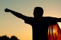 Man in the costume superhero standing in the park at sunset time