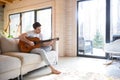 Man on couch with guitar Royalty Free Stock Photo