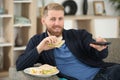 man on couch watching tv and eating sandwich Royalty Free Stock Photo