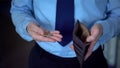 Man counting coins left to next salary, low income, lack of money, poverty