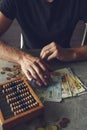 Man counting money on gray table with abacus and euro banknotes Royalty Free Stock Photo