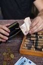 Man counting money with abacus on wooden background, top view. Financial concept