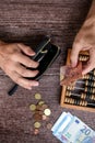 Man counting money with abacus on wooden background, top view. Financial concept