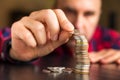 Man counts his coins on a table