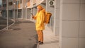 Man courier in yellow clothes delivers food - standing near the porch