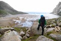 Young man with backpack standing on a rock and looking to Bunes Beach on Lofoten Islands in Norway. Royalty Free Stock Photo